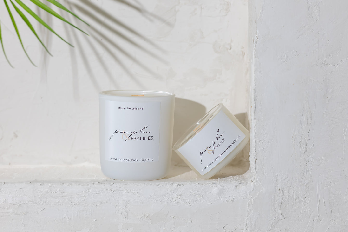 White candle with the scent Pumpkin & Pralines on a label on a white surface