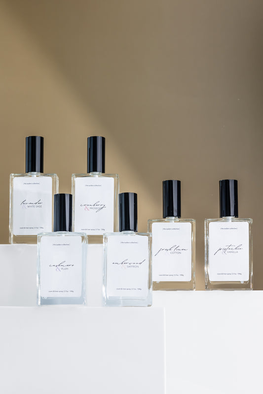 Six alcohol-free, non-toxic room sprays in assorted scents arranged on a tabletop, perfect for refreshing any room.