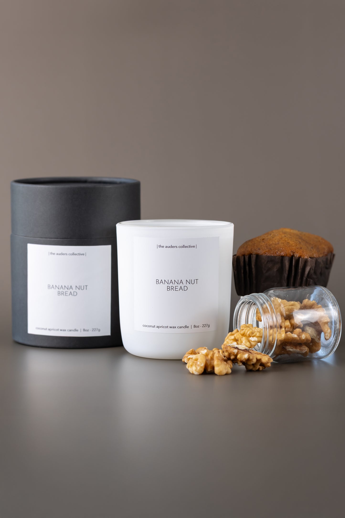 Candle labeled 'Banana Nut Bread' with a banana loaf and walnuts on a gray surface