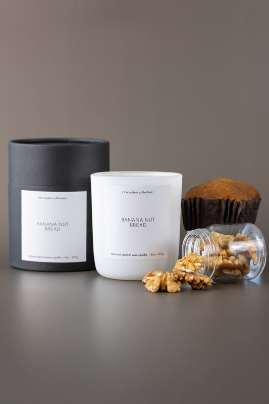 Candle labeled 'Banana Nut Bread' with a banana loaf and walnuts on a gray surface