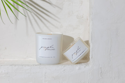 White candle with the scent Pumpkin & Pralines on a label on a white surface