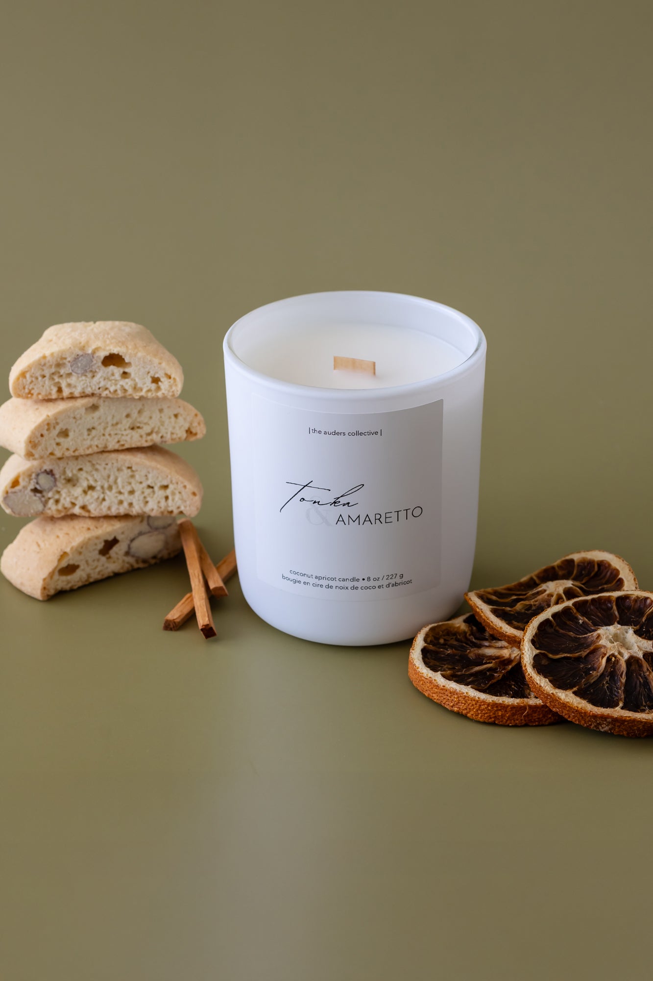 A Tonka & Amaretto scented candle with an almond biscotti and orange slice beside