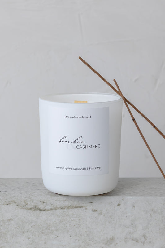 White candle labeled 'Bamboo Cashmere' on a light surface with a neutral background