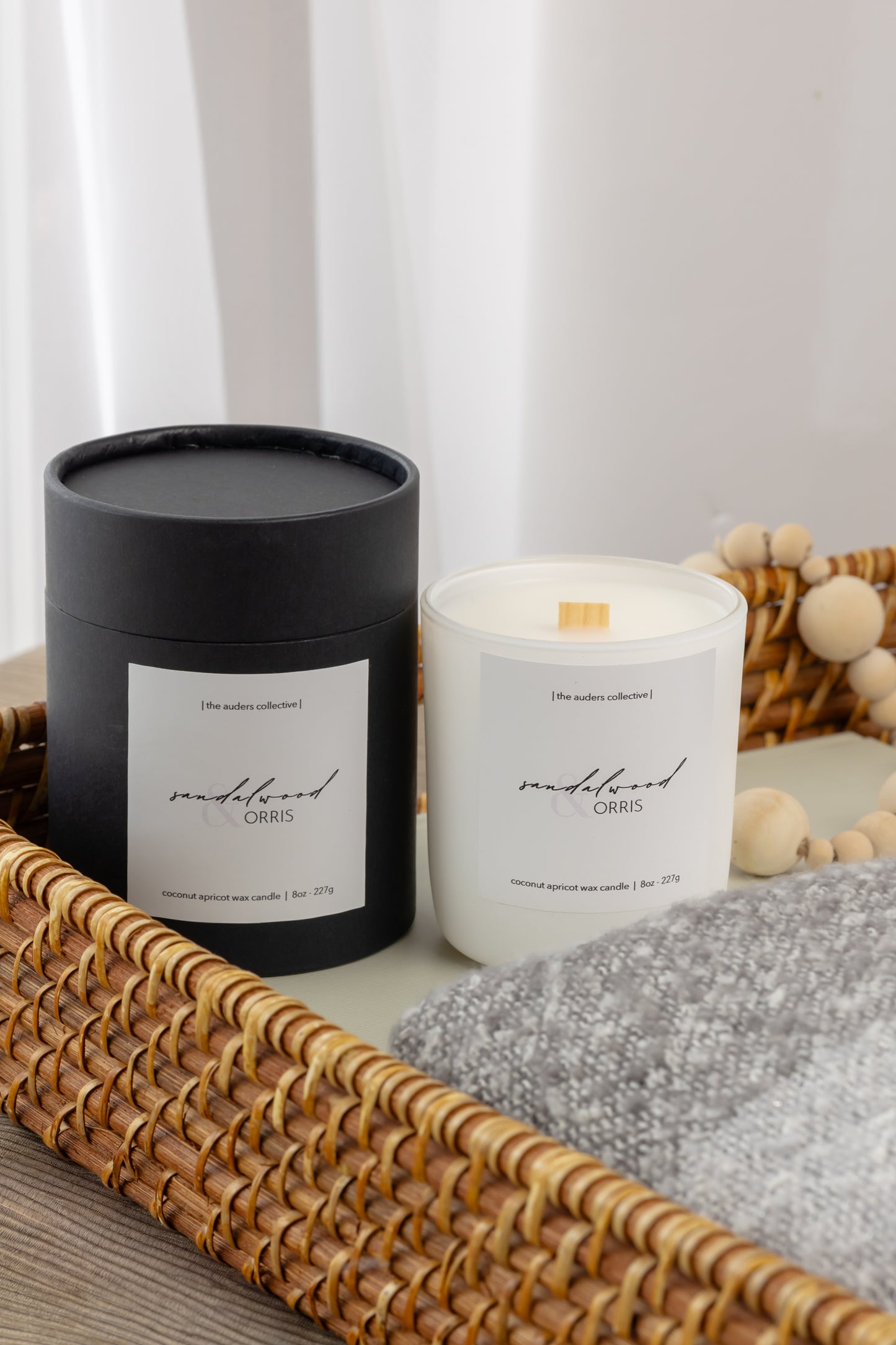 8oz White candle on minimalist background with a wicker basket, scent on label says sandalwood and orris 